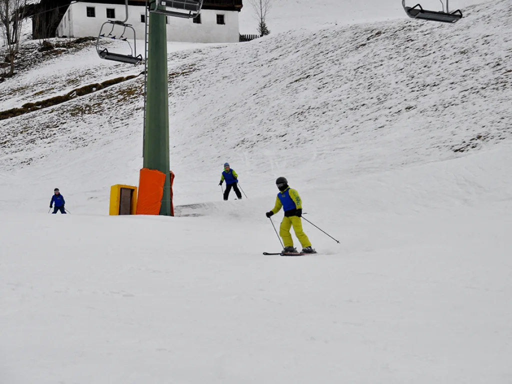 Drei Skifahrende auf dem Hang unterhalb der Bergstation.